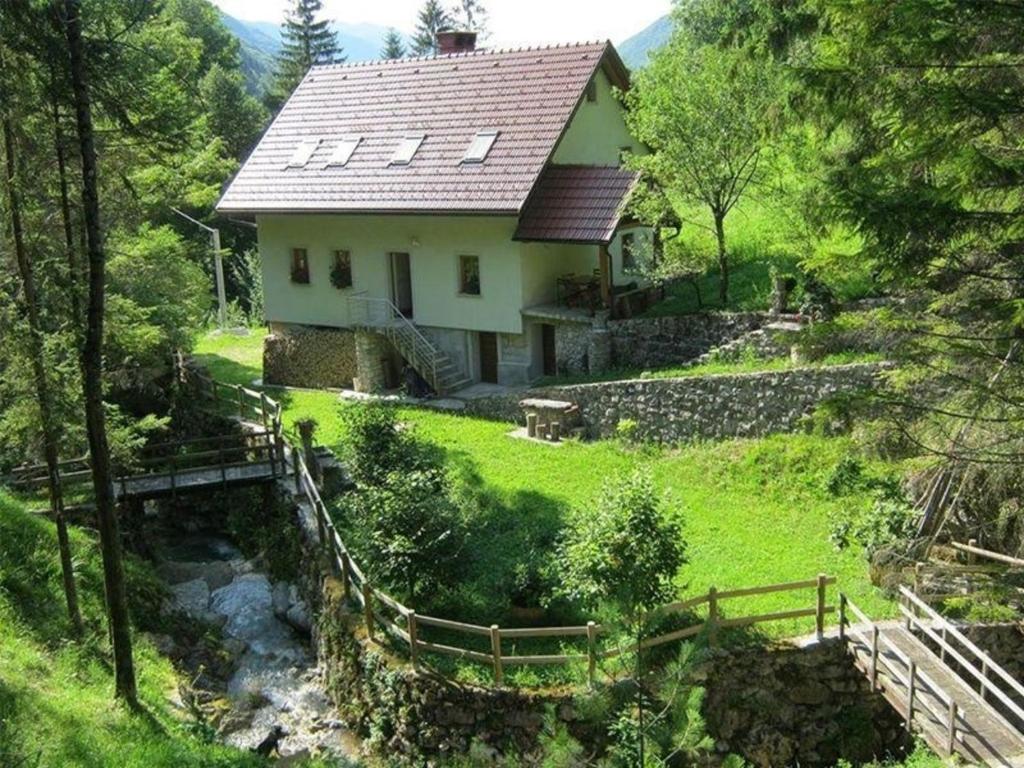 uma casa numa colina com um riacho à frente em Ferienhaus für 8 Personen ca 189 qm in Dolenja Trebuša, Küstenland Slowenien em Dolenja Trebuša