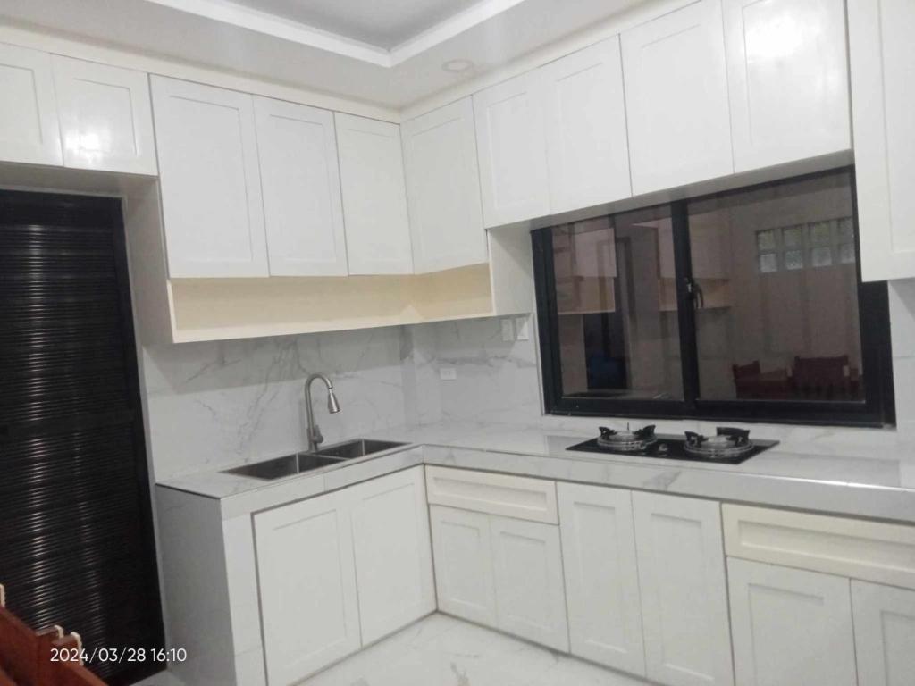 a white kitchen with white cabinets and a sink at MaNelly Guest House Hotel in Donsol