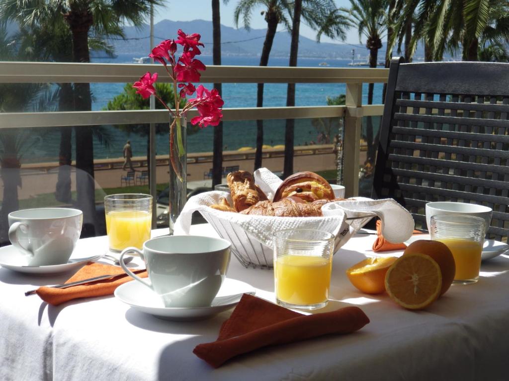 カンヌにあるAppartement Rottaro luxueux 2 ch 2 sdb face à la merのオレンジジュースとパンの朝食付きテーブル