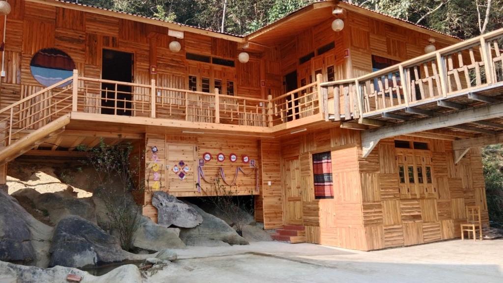 a large wooden house with a balcony and stairs at Higland Homestay Bac Ha in Bắc Hà
