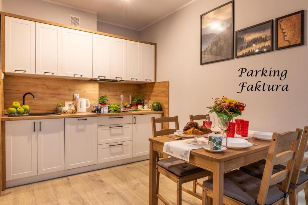 a kitchen with white cabinets and a wooden table at Apartament Słoneczny Poranek in Ustrzyki Dolne