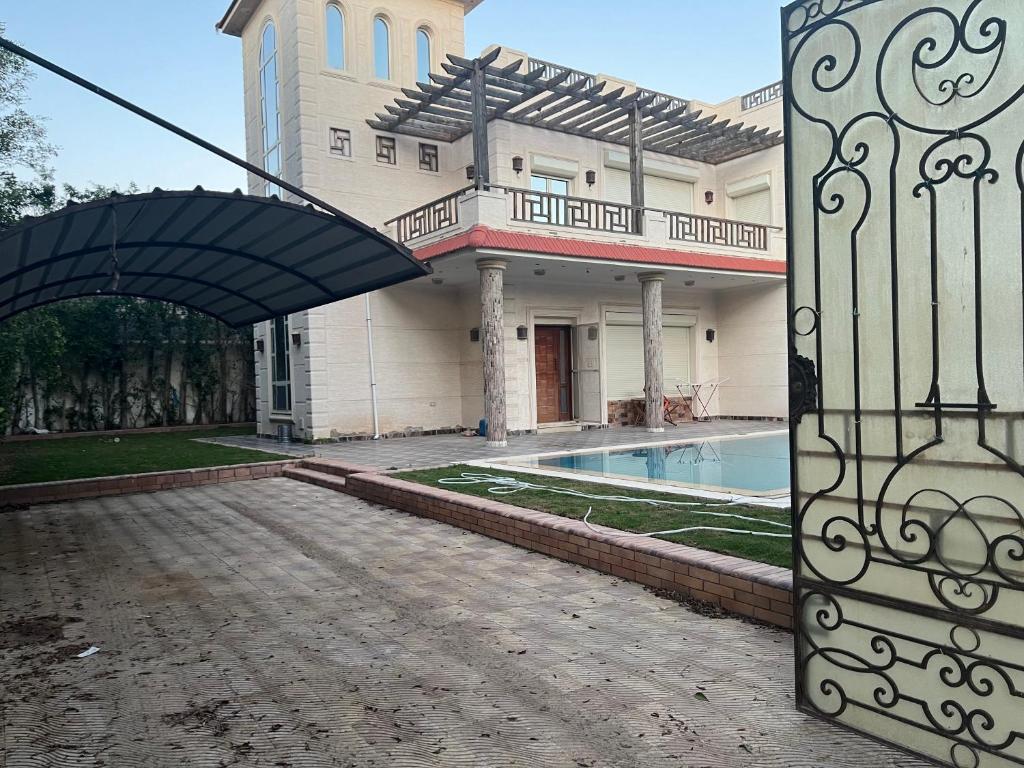 ein Gebäude mit einem Tor und einem Pool in der Unterkunft El dakroury king mariout villa in Naj‘ al Aḩwāl