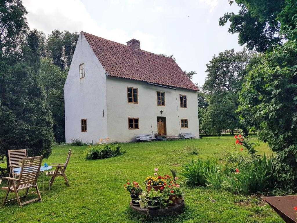 a white house with a yard with chairs and flowers at Genuine Gotland house with large garden in Roma in Romakloster