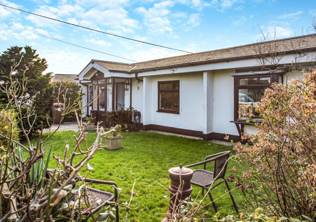 a white house with a yard with a chair at Gilfach Ceidio in Morfa Nefyn