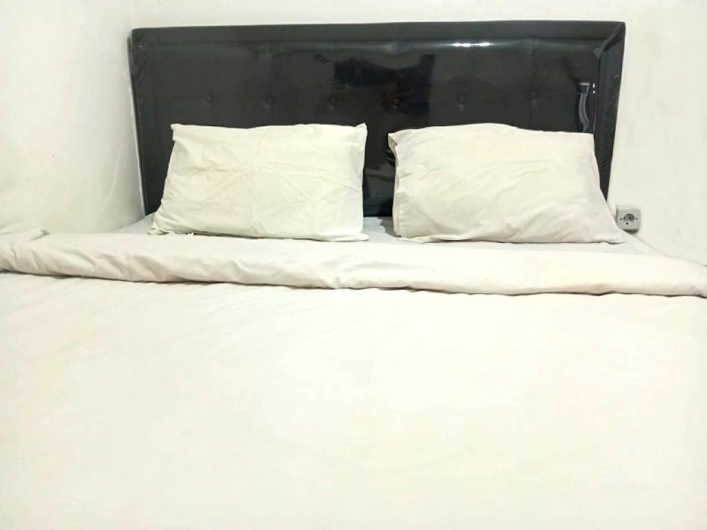 Una cama blanca con dos almohadas encima. en Saijaan Yogyakarta Mitra RedDoorz, en Kejayan