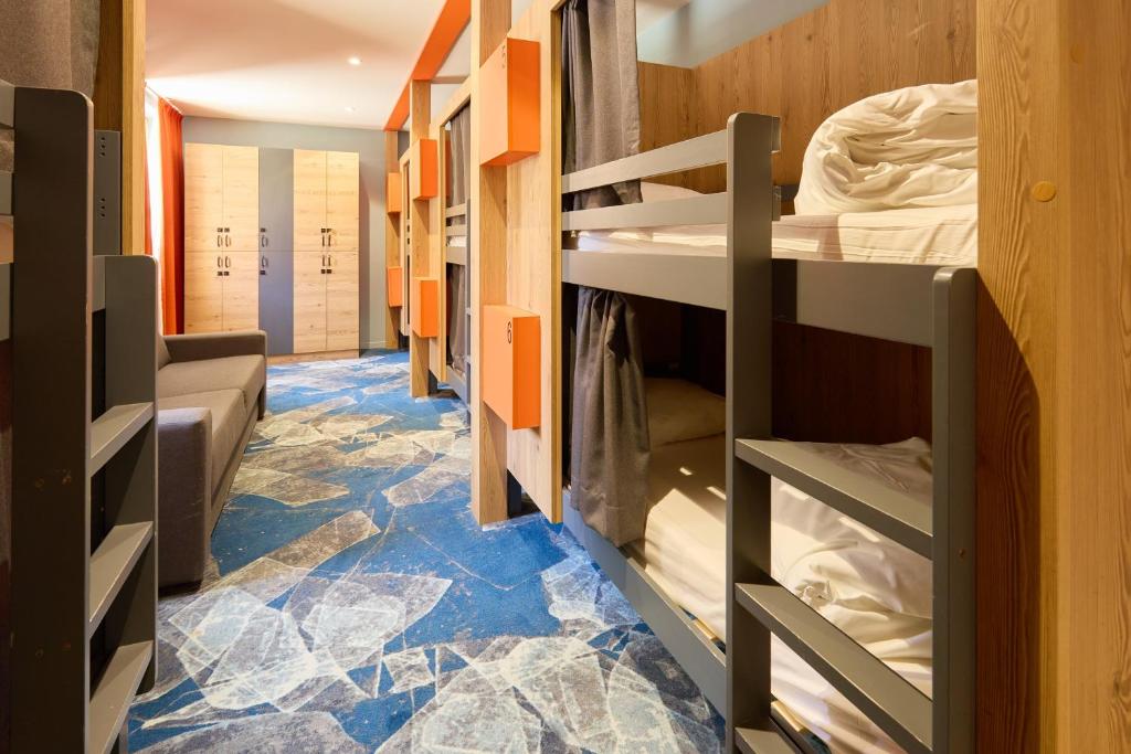 a room with bunk beds with a blue floor at Hotel Base Camp Lodge - Albertville in Albertville