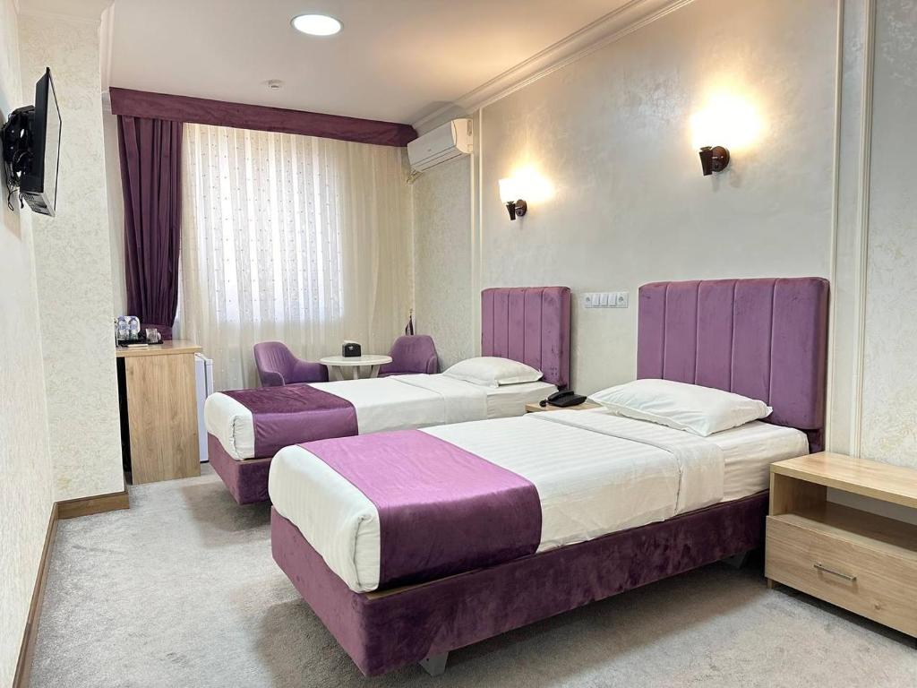 2 łóżka w pokoju hotelowym z fioletowymi meblami w obiekcie Aurora Hotel w Taszkiencie