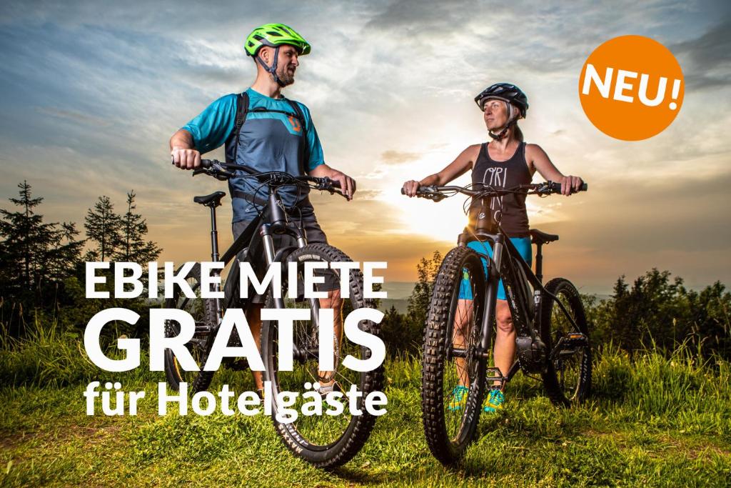 dwoje ludzi jeżdżących rowerami w polu ze słowami motocykl mil miast furridge w obiekcie k1 sporthotel w mieście Kurort Oberwiesenthal