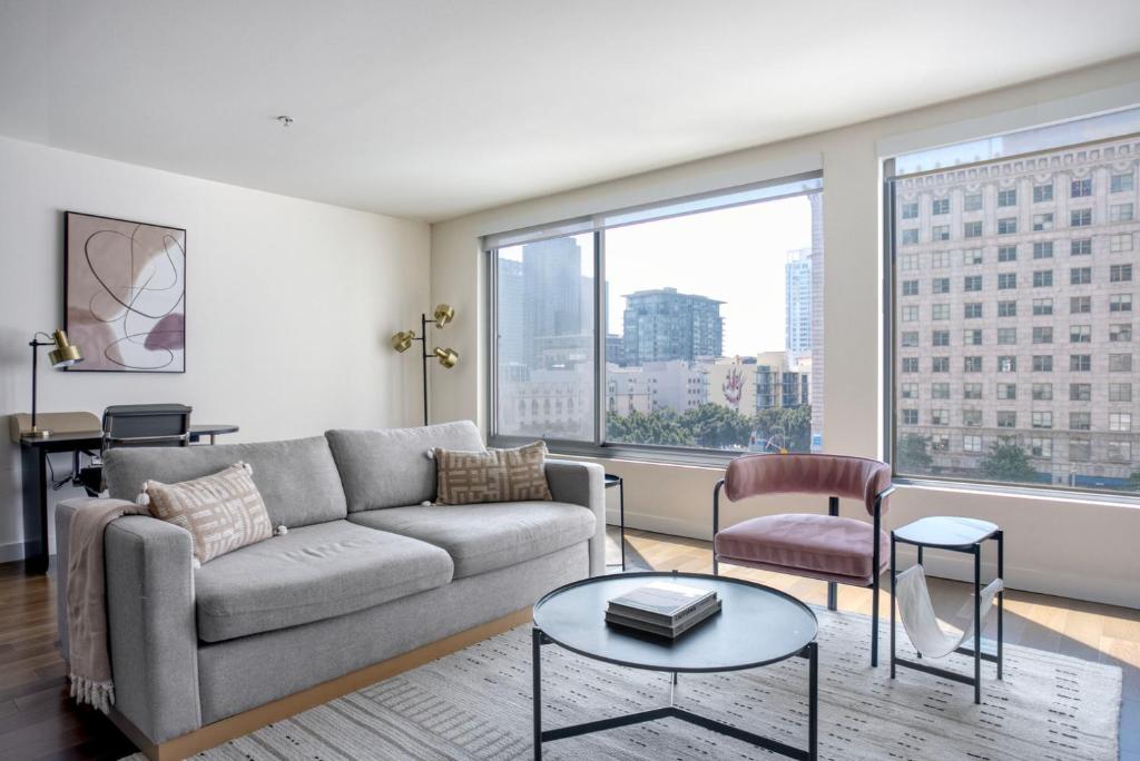 ロサンゼルスにあるBlueground DTLA pool courtyard near dining LAX-1202のソファと大きな窓のあるリビングルーム