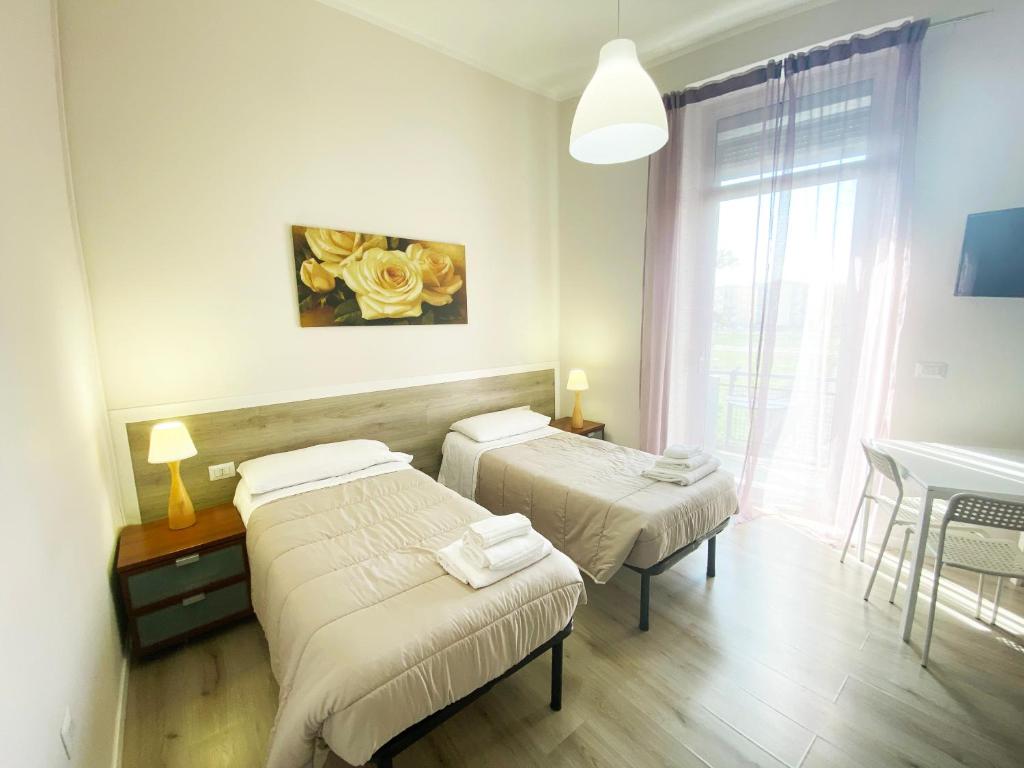 a room with two beds and a table and a window at EASYROOMS ONE in Parma