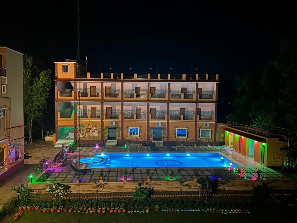 budynek z basenem przed nim w nocy w obiekcie Resort Neel Nirjan w mieście Bolpur