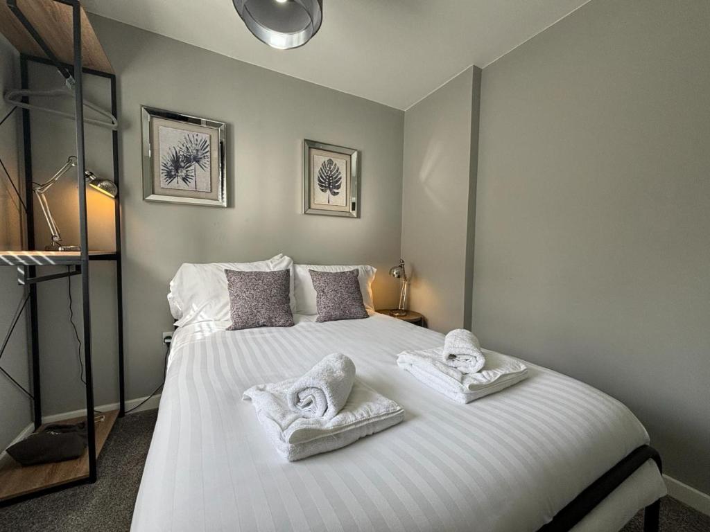 sypialnia z dużym białym łóżkiem z ręcznikami w obiekcie Flat 1 Castle Street Serviced Apartments w mieście Telford