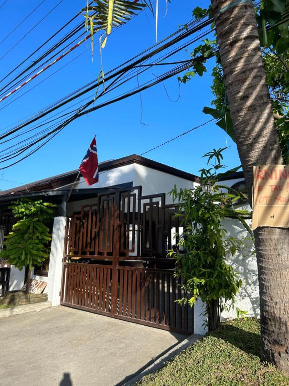 a house with a gate and a tree at Loidas Place in Talisay