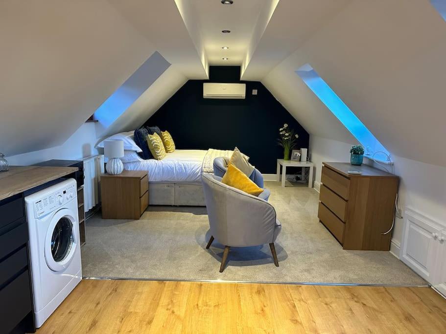 a attic bedroom with a bed and a chair at Stunning studio flat with own large garden in Shrewsbury SLEEPS 2 in Shrewsbury