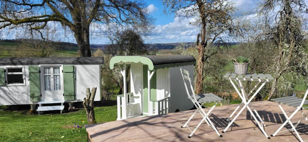 a couple of chairs sitting on a deck next to a house at Petit a Petit - gypsy wagons and Bell tents in the Bourgogne in Saisy