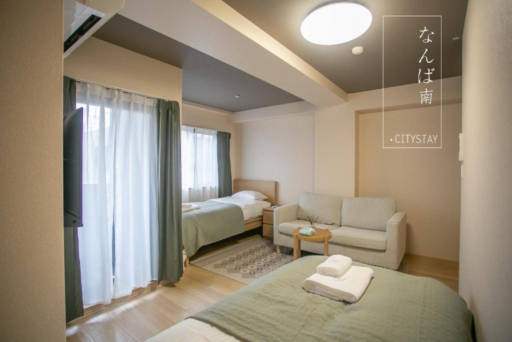 a room with two beds and a living room with a couch at CityStay難波南 in Osaka