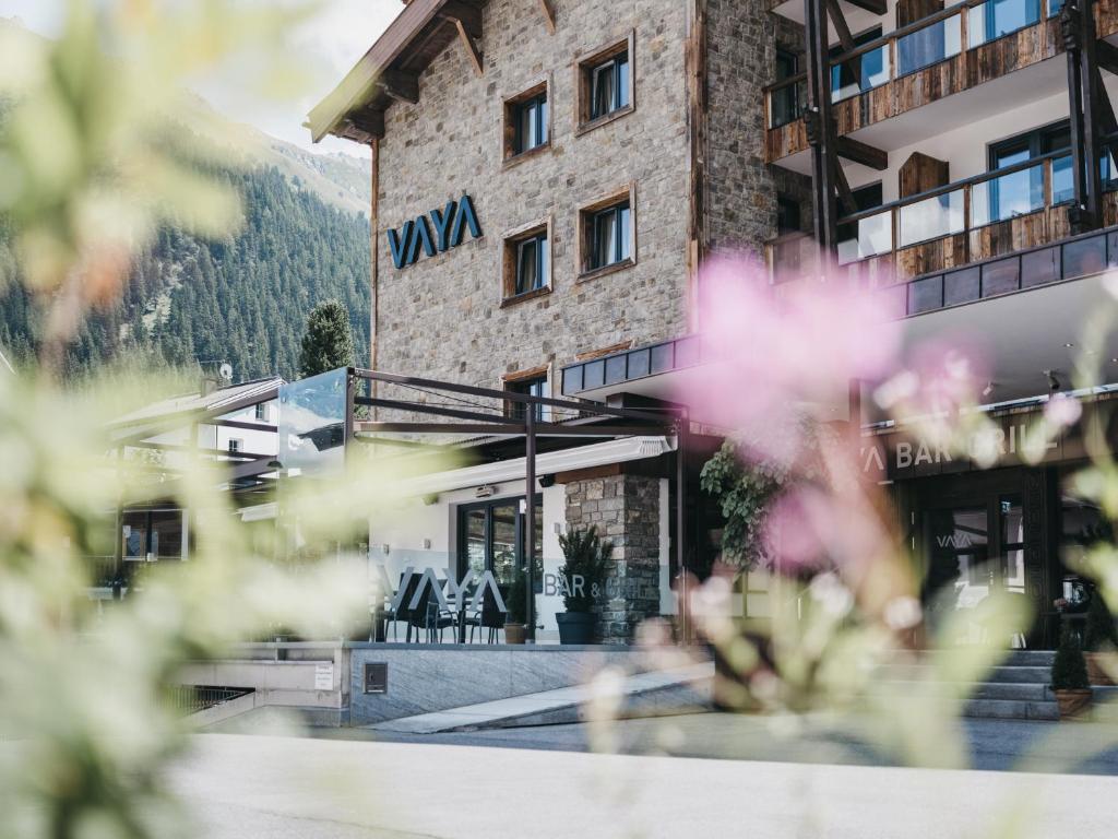 a hotel building with tables and chairs in front of it at VAYA Galtür Paznaun in Galtür