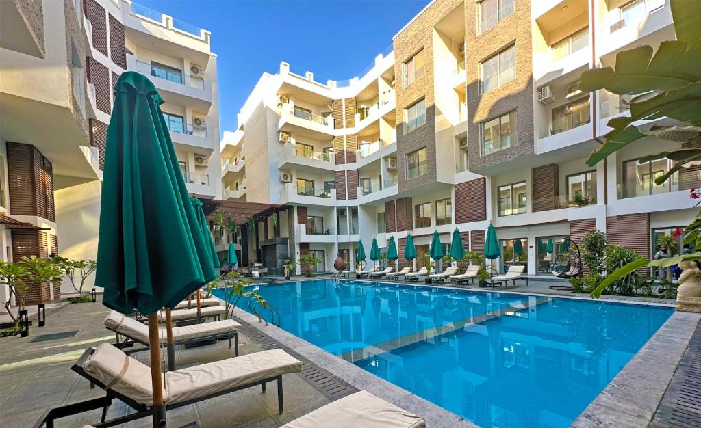 a swimming pool with chairs and a umbrella and some buildings at Imperial Resort Apartment XL 1 Bed in Hurghada