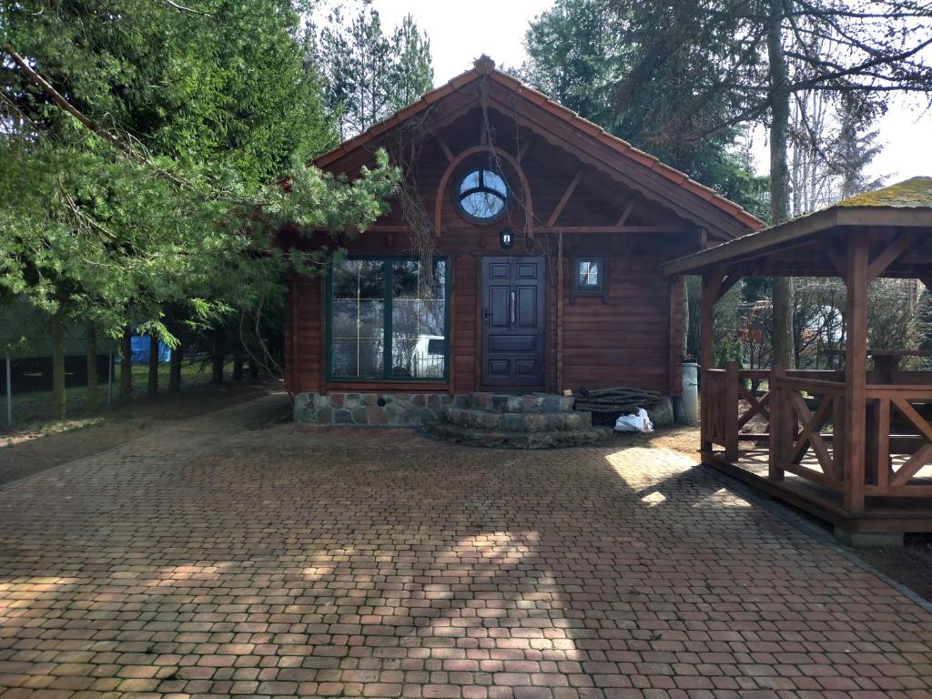 a small wooden building with a clock on it at Domki nad Jeziorem Ołów in Ryn