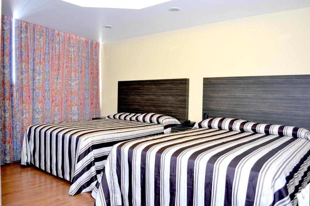 2 camas en una habitación con sábanas a rayas en Hotel Arizona, en Ciudad de México