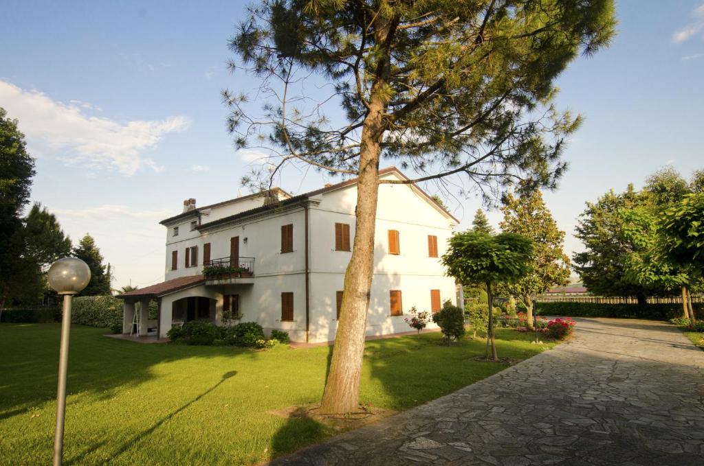 uma casa branca com uma árvore no quintal em La Coccinella em Iesi