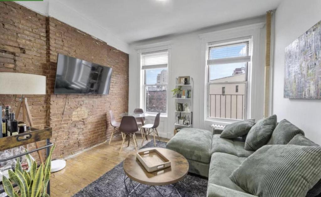 a living room with a couch and a brick wall at 1 Bedroom Apartment East Village Union Square in New York