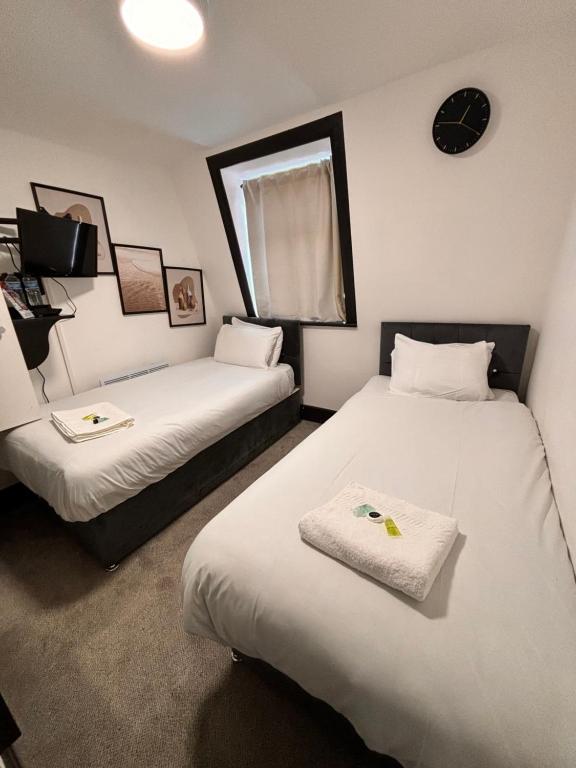 ロンドンにあるIvy House Hotelのベッド2台と壁掛け時計が備わる客室です。