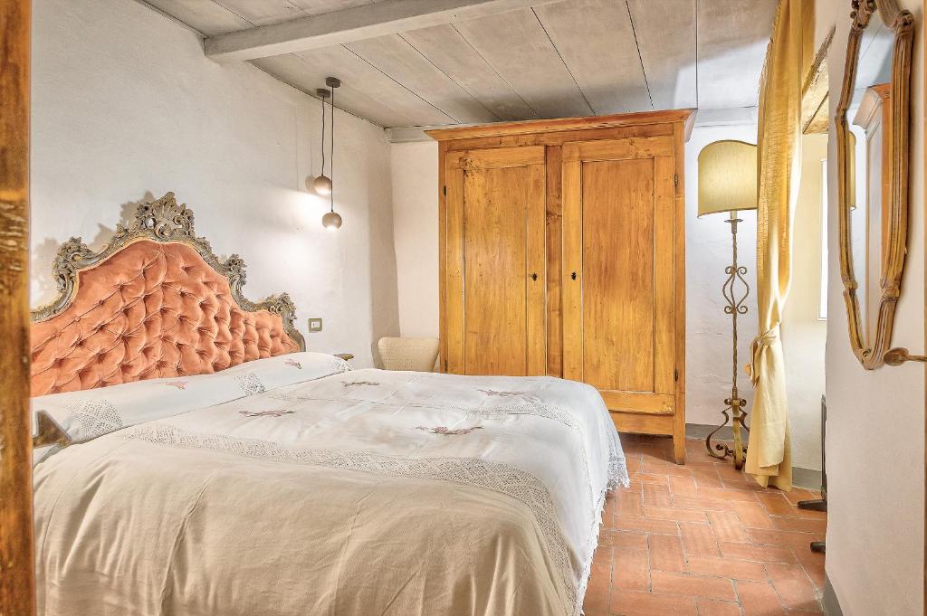 een slaapkamer met een groot bed en een houten hoofdeinde bij La Bomboniera - Together in Tuscany in Cortona