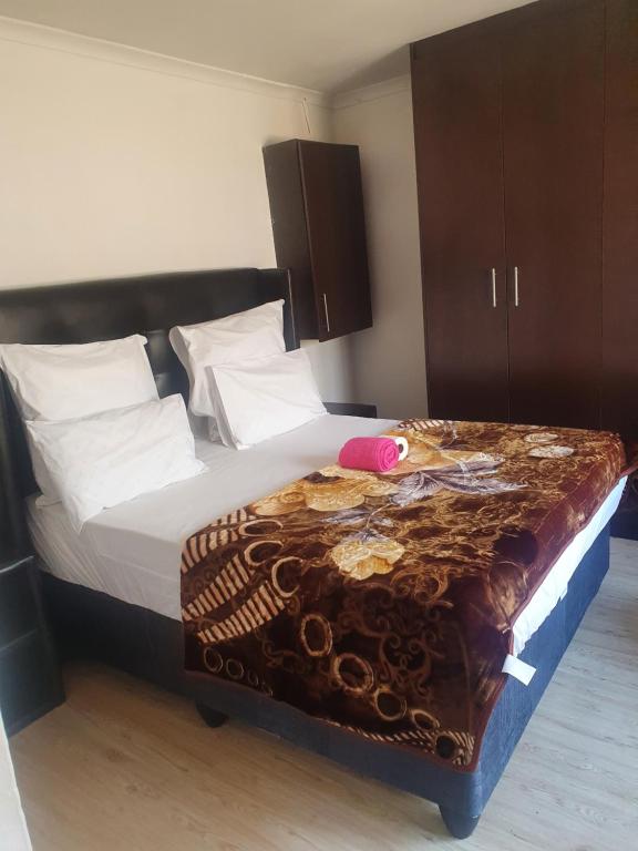 um quarto com uma cama grande e um cobertor castanho em Ludinz guest house na Cidade do Cabo