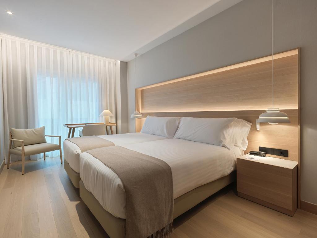 una habitación de hotel con una cama grande y una mesa en Zenit Coruña en A Coruña