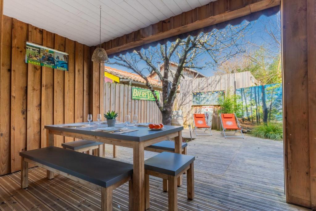 une terrasse en bois avec une table et des chaises dans l'établissement Comme Un Petit Chalet, à La Teste-de-Buch