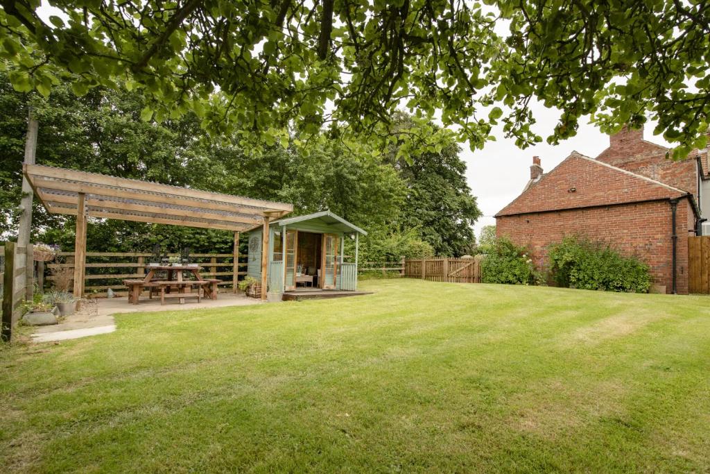 a picnic shelter in a garden next to a brick building at Lime Kiln Farm in Malton