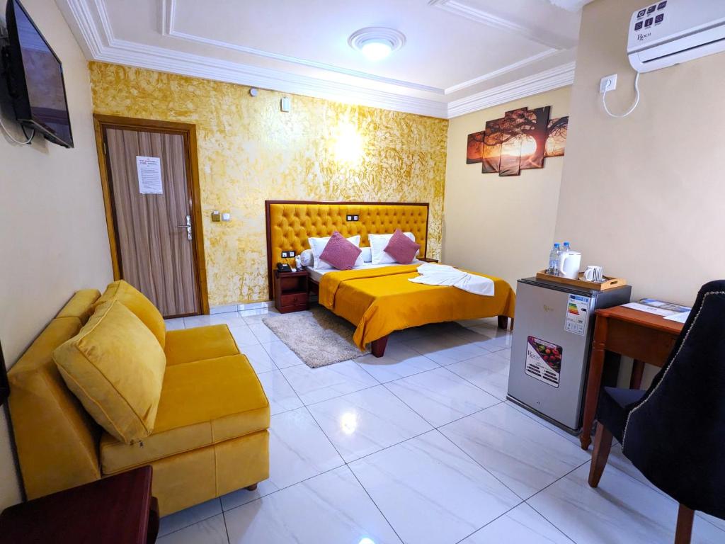 um quarto de hotel com uma cama amarela e um sofá em ALICIA HOTEL em Douala