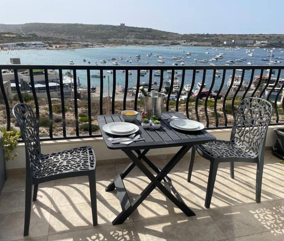 einen Tisch und Stühle auf einem Balkon mit Meerblick in der Unterkunft Mellieha Bay Seafront 1bed Penthouse in Mellieħa
