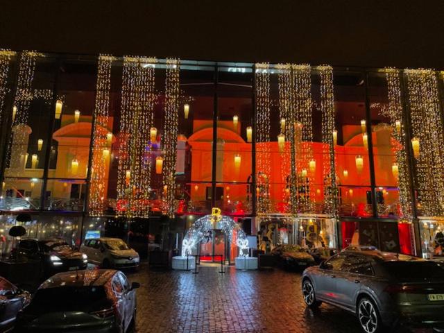 un bâtiment avec des lumières de Noël et des voitures garées dans un parking dans l'établissement studio avec terrasse en face la gare d’Enghien a 15 minute de paris gare du nord et a 10 mn de stade de France, à Enghien-les-Bains