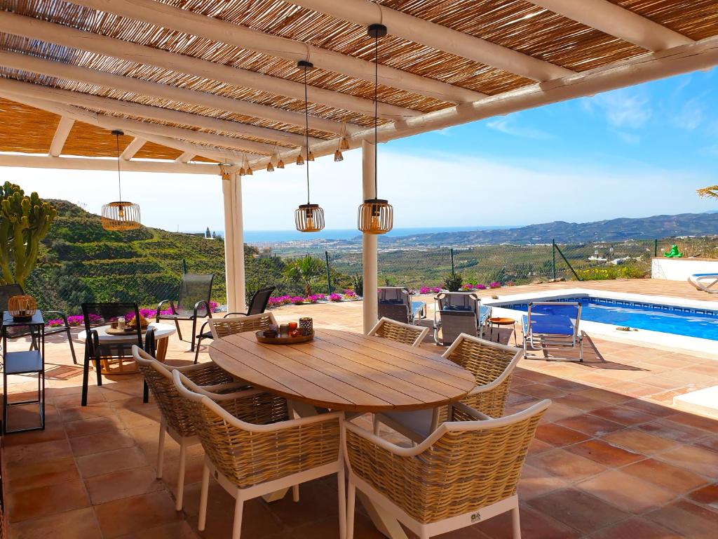 a patio with a wooden table and chairs and a pool at Casa La Aurora in Arenas