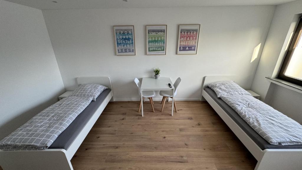 2 camas en una habitación con mesa y silla en Privates Messe/Monteuerzimmer en Heiligenhaus