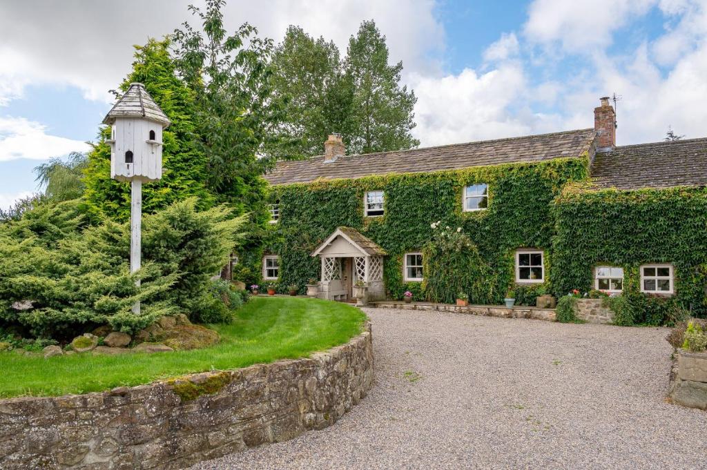 una casa con una casa de pájaros delante de ella en Sun Hill Farmhouse, en Leyburn