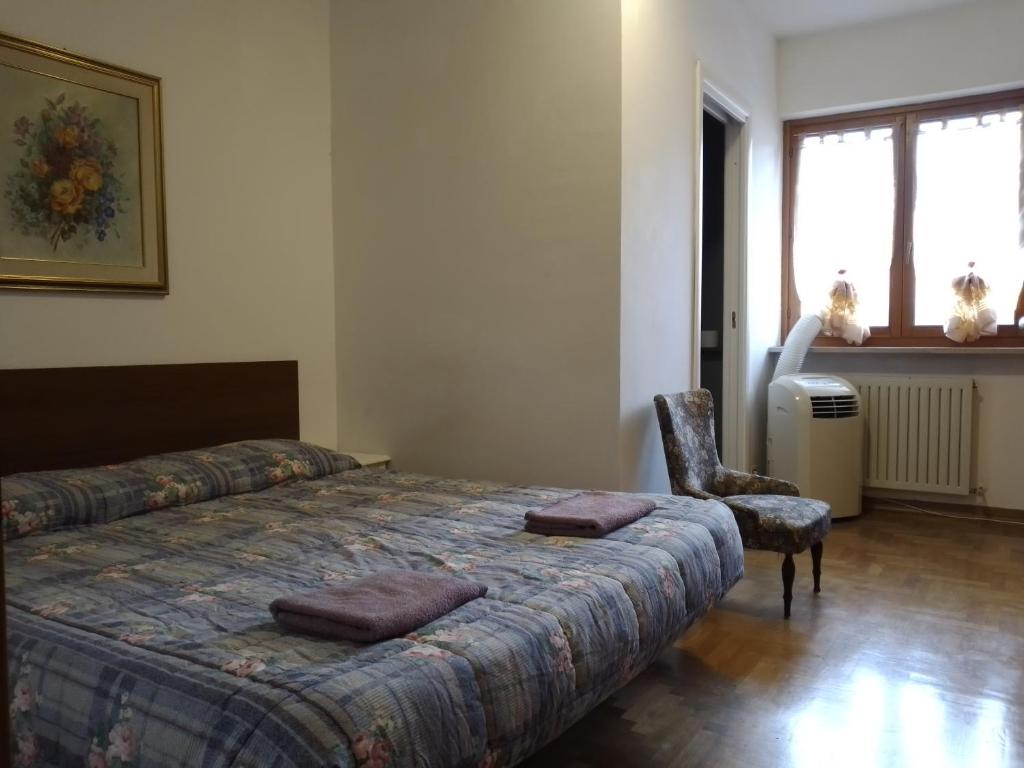 um quarto com uma cama, uma cadeira e uma janela em Cjase Paola em Cassacco