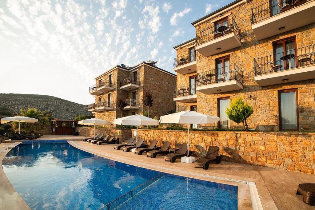 a hotel with a swimming pool with chairs and umbrellas at Limnos Otel in Gokceada Town