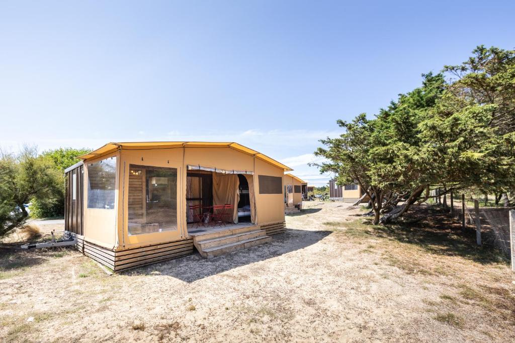 ein kleines Haus auf einem Feld mit Bäumen in der Unterkunft Huttopia Ars-en-Ré in Ars-en-Ré