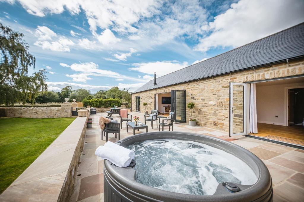 a hot tub on the patio of a house at Millfield Barn in Richmond