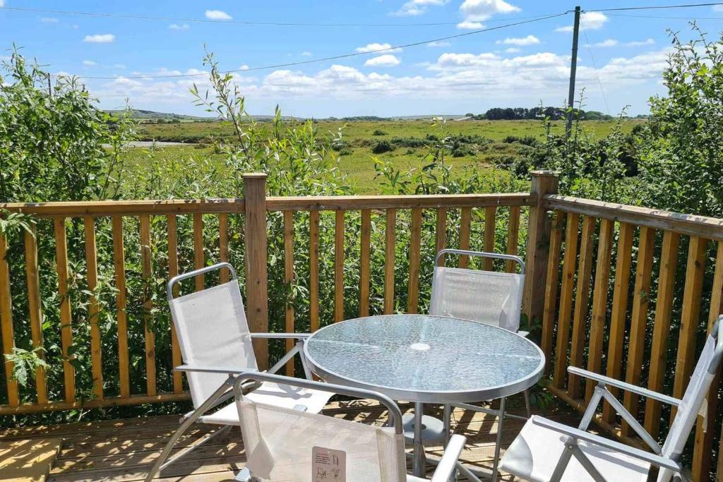 a glass table and two chairs on a deck at Stable Barn Apartment in Saint Breward