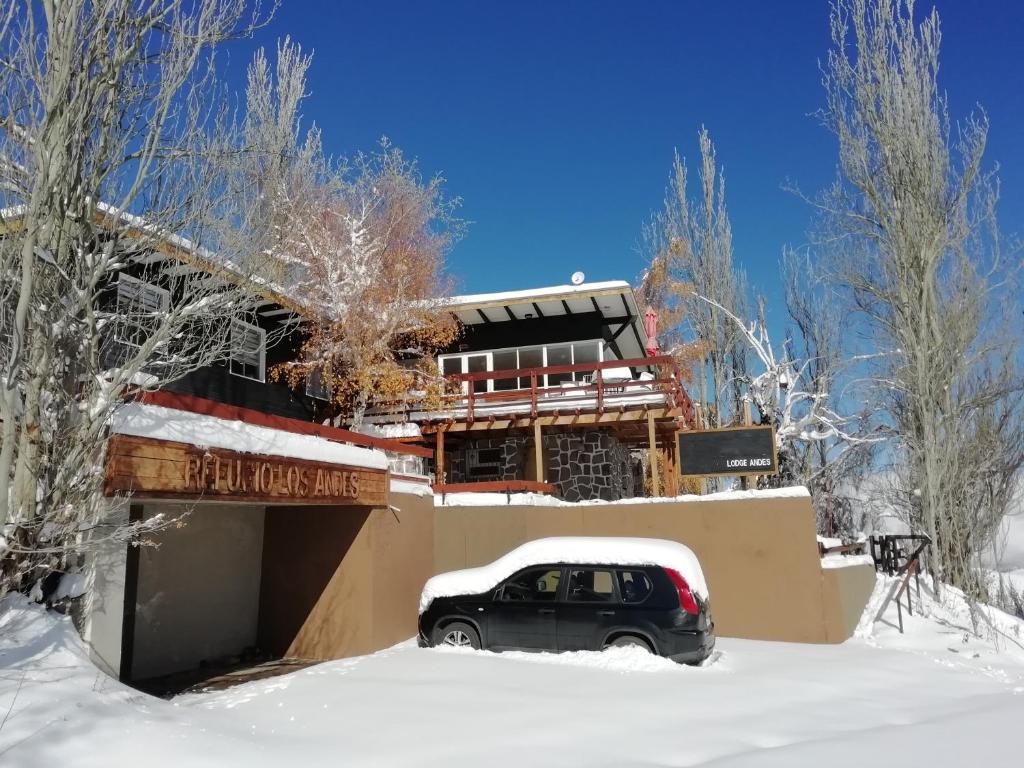 a car parked in front of a building in the snow at Lodge Andes in Farellones