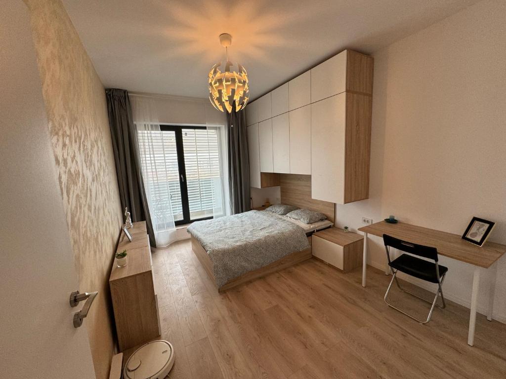 a bedroom with a bed and a desk and a chandelier at Miraculous Luxury Apartment in Bucharest