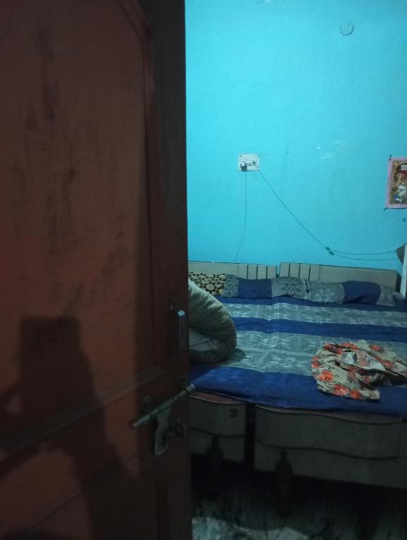 Cama pequeña en habitación con pared azul en Meera rai house, en Dehradun