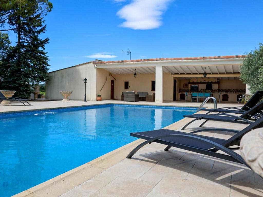 a swimming pool with lounge chairs next to a building at Holiday Home Cucuron by Interhome in Cucuron