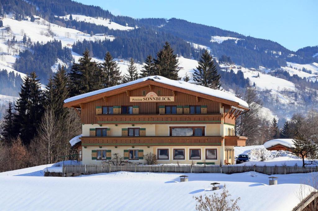 a large building in the snow in front of a mountain at Pension Sonnblick in Westendorf