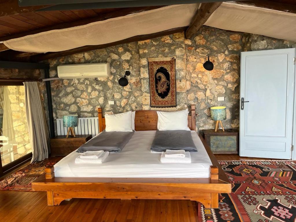 a bedroom with a large bed in a stone wall at Kale Lodge - Adult Only + 15 in Kas