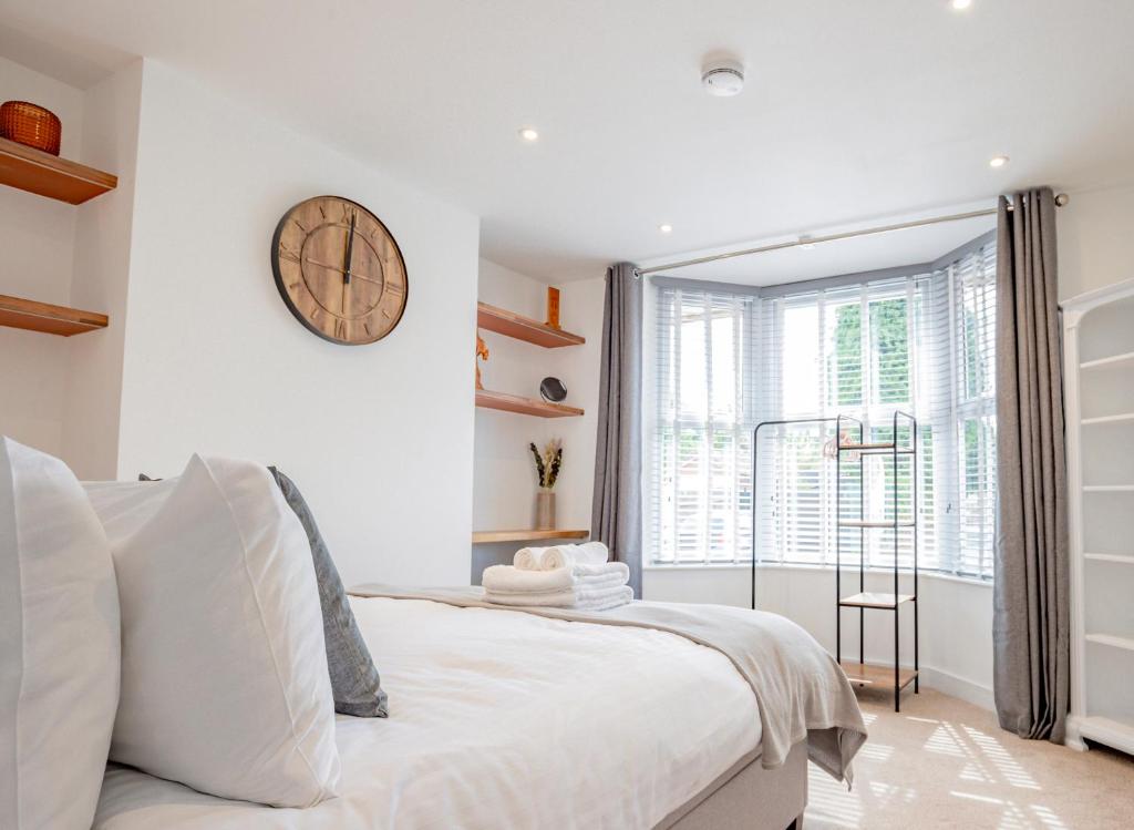 a bedroom with a bed with a clock on the wall at Modern flat with garden in city centre in Hereford